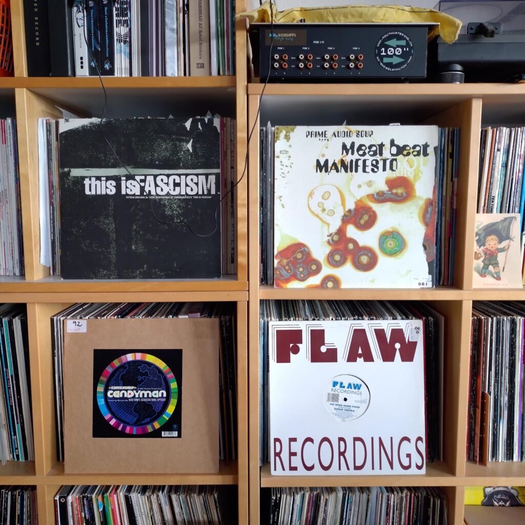 A wall of records with 4 records exposed to the front. Consolidated - This Is Fascism. Meat Beat Manifesto - Prime Audio Soup. Cornershop - Candyman. Queer Cheeba - We Need More Food