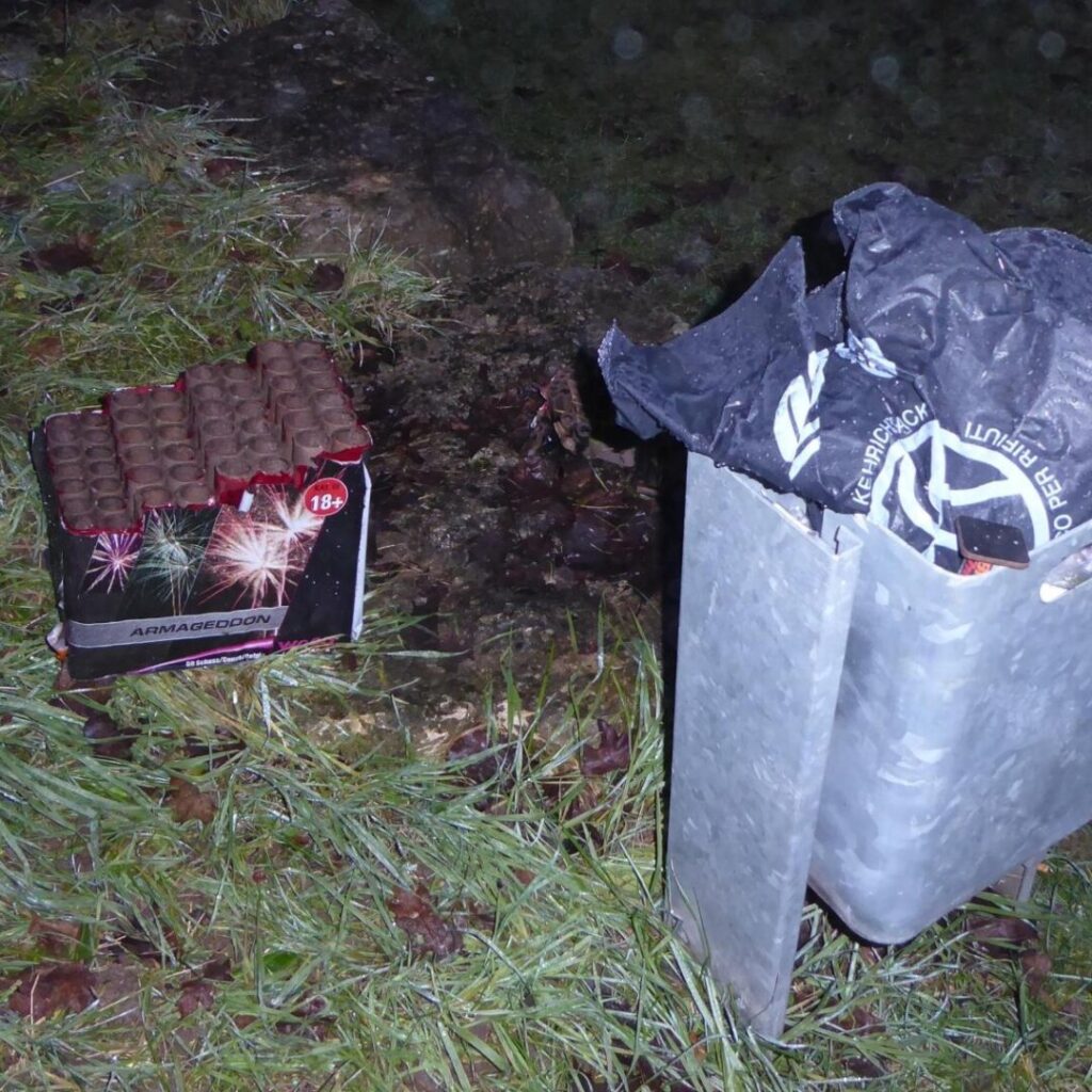Night shot of a garbage can after a night of fireworks, on the floor a spent cardboard box named Armageddon
