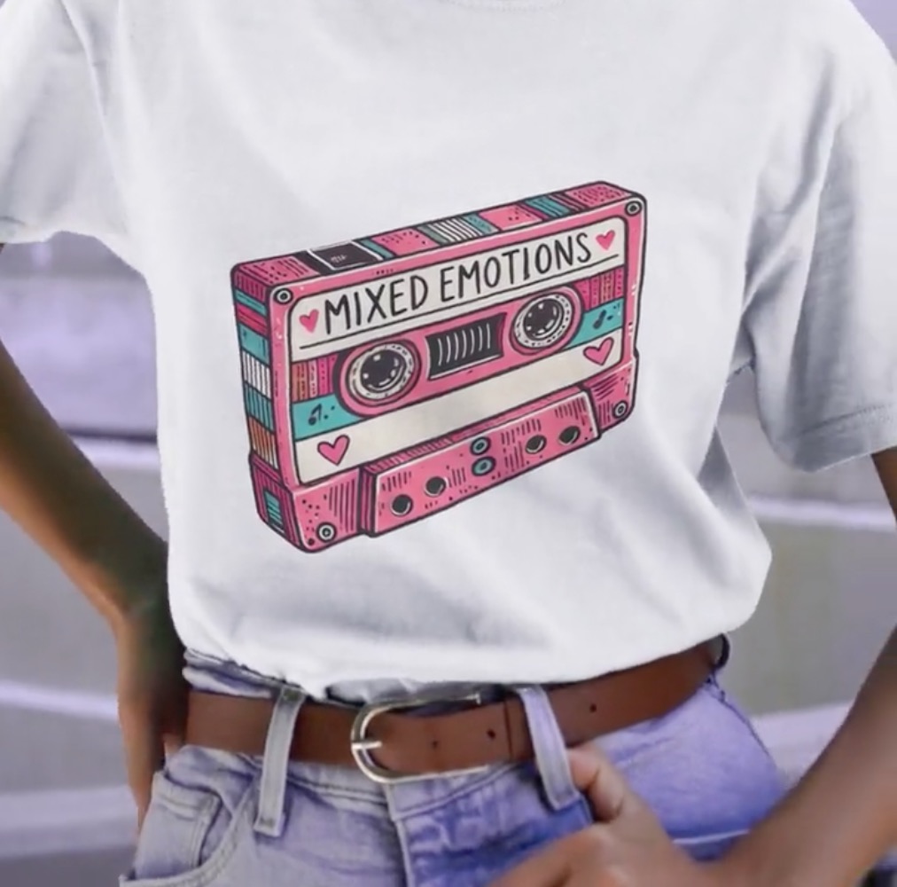 A person wears a t-shirt with a graphic of a cassette tape that is named "mixed emotions'