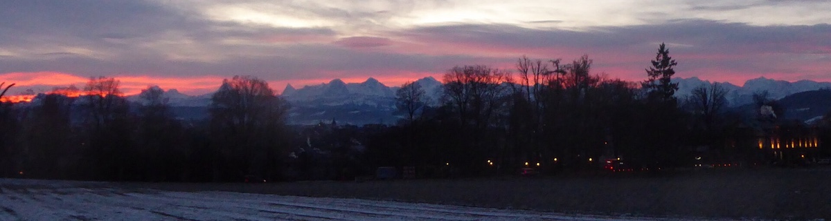 Dramatic colors over a mountain range with the city of Bern in the foreground