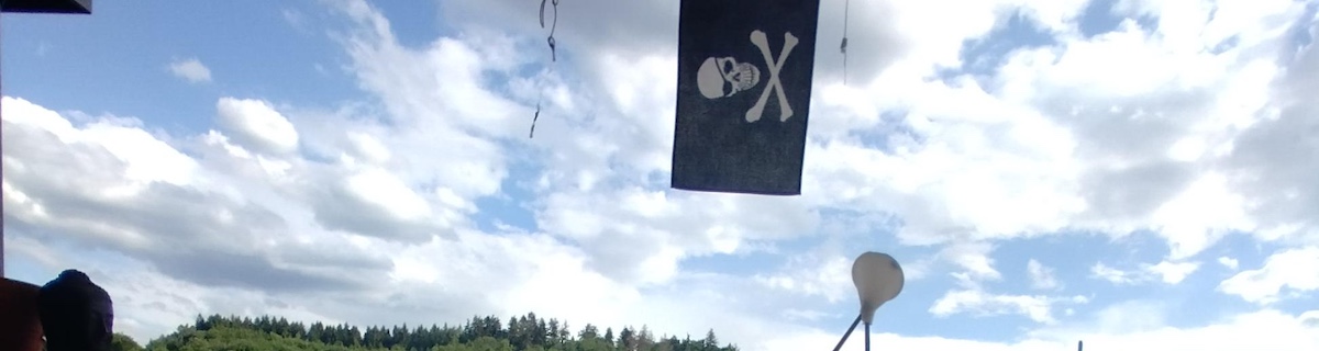 A blue sky with some clouds, a pirate flag, a black clay buddha head.